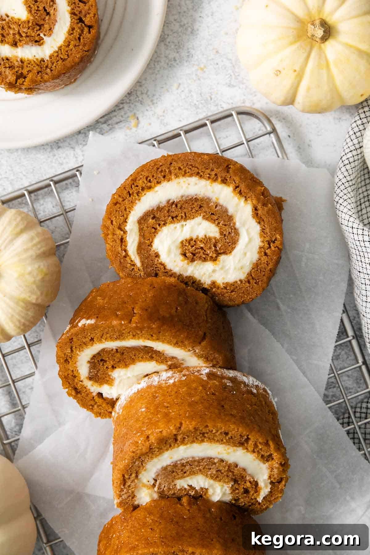 Slices of perfectly rolled gluten-free pumpkin roll cooling on a wire rack with parchment paper underneath.