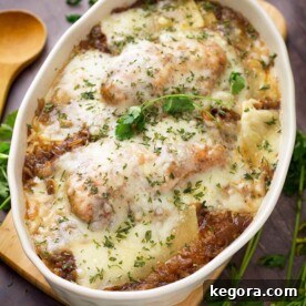 French Onion Chicken and Rice in a white oval shaped bowl on a small wooden board