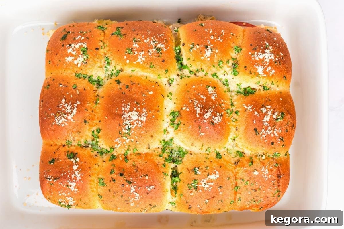 Italian Sub Sliders baked in a 9x13 baking dish, topped with parmesan, ready to be sliced and served.