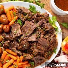 Apple Cider Pot Roast on a white platter with carrots and potatoes.