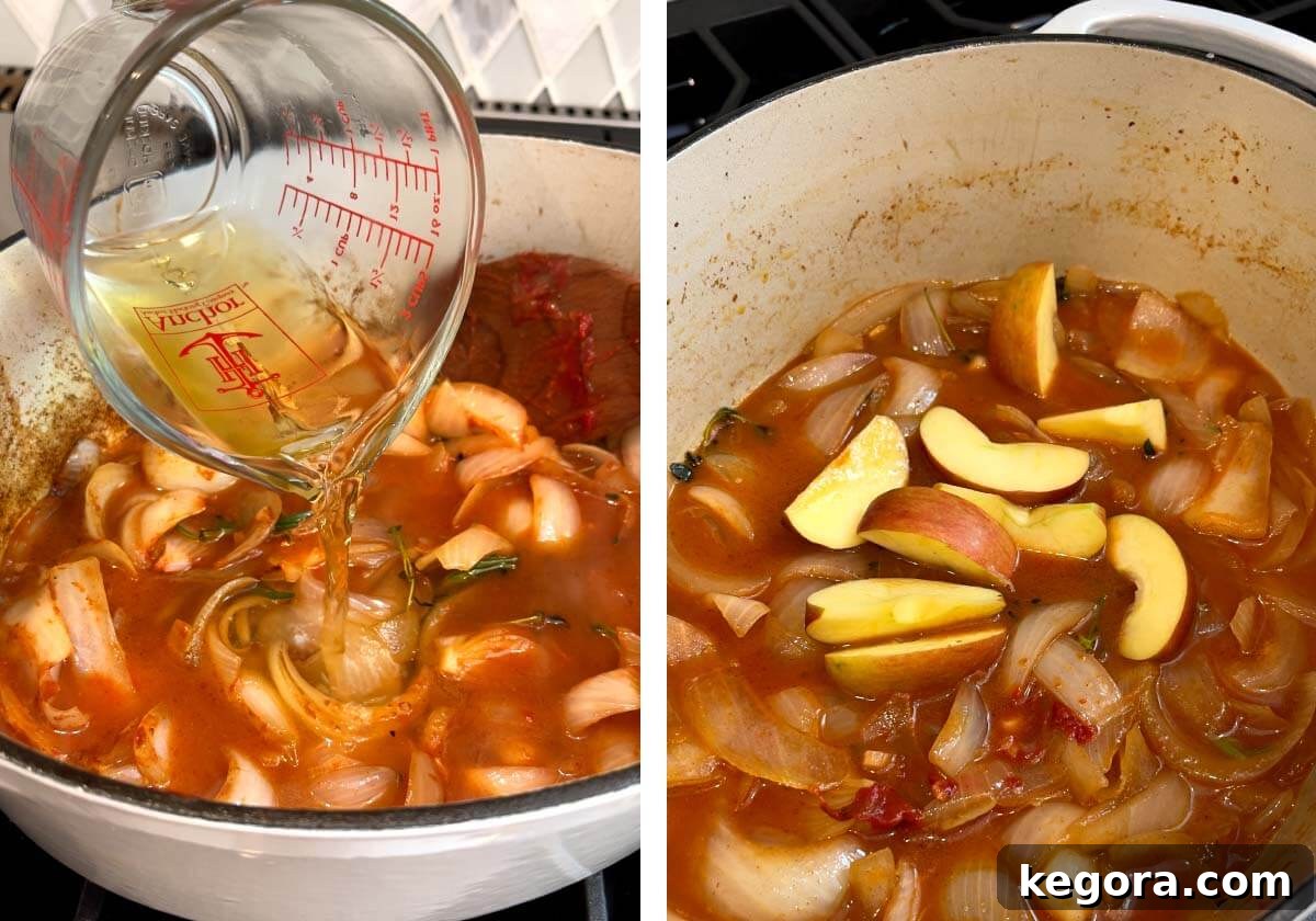 Apple cider and chicken broth being poured into the Dutch oven with the aromatics, along with chopped apple pieces.