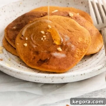 Three golden-brown pumpkin protein pancakes stacked on a plate, ready to be served.