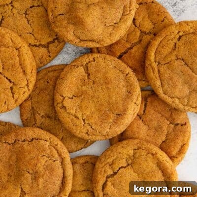 An overhead view of several chewy gluten-free pumpkin snickerdoodles layered on top of each other, dusted with cinnamon sugar.