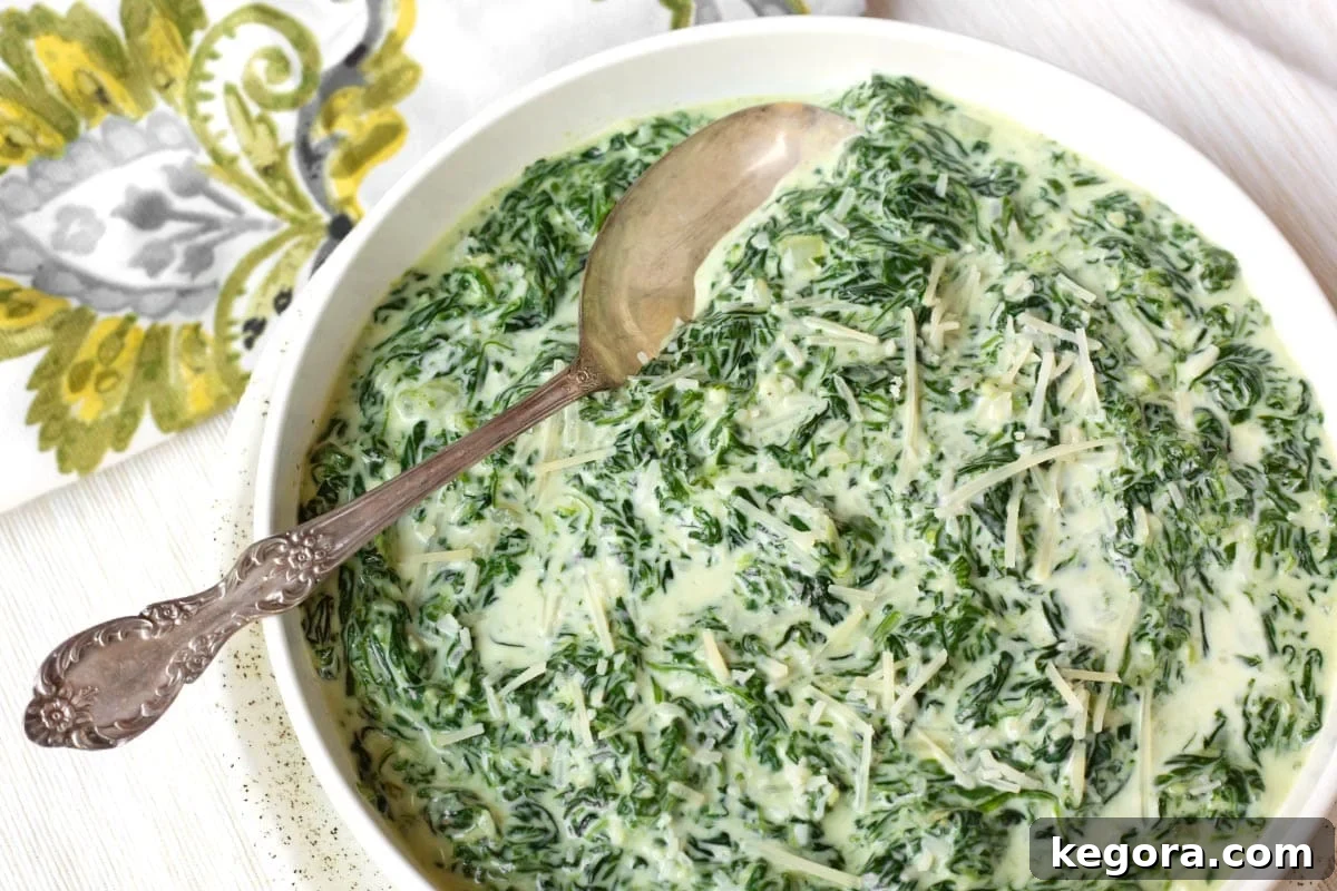 Rich Creamy Cheesy Spinach 11 Cheesy Creamed Spinach in a white serving bowl with a spoon.