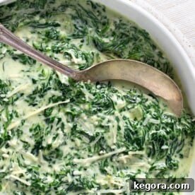 Rich Creamy Cheesy Spinach 12 Cheesy Creamed Spinach in a bowl with spoon closeup.
