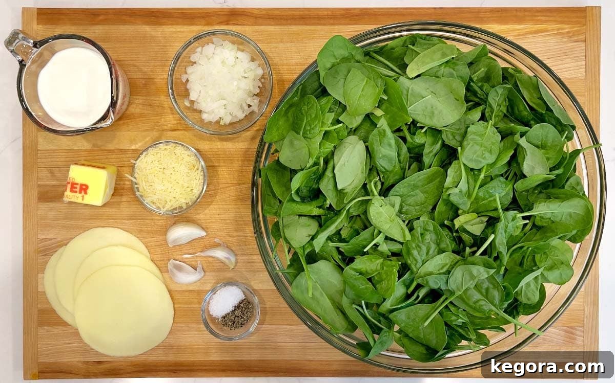 Rich Creamy Cheesy Spinach 4 Ingredients for cheesy creamed spinach laid out on a wooden board, including fresh spinach, butter, onion, garlic, half and half, provolone, and parmesan cheese.