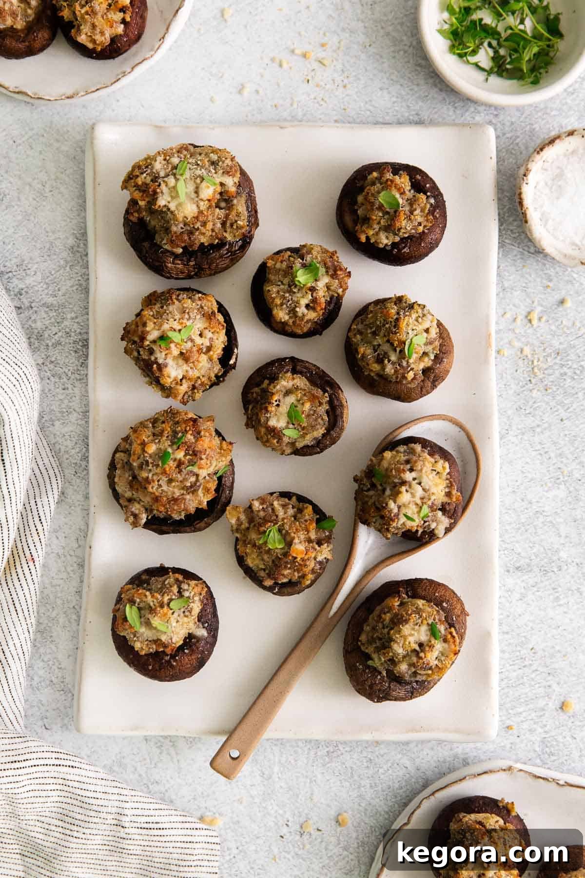 A platter of gluten-free stuffed mushrooms with a serving spoon, garnished with fresh parsley.