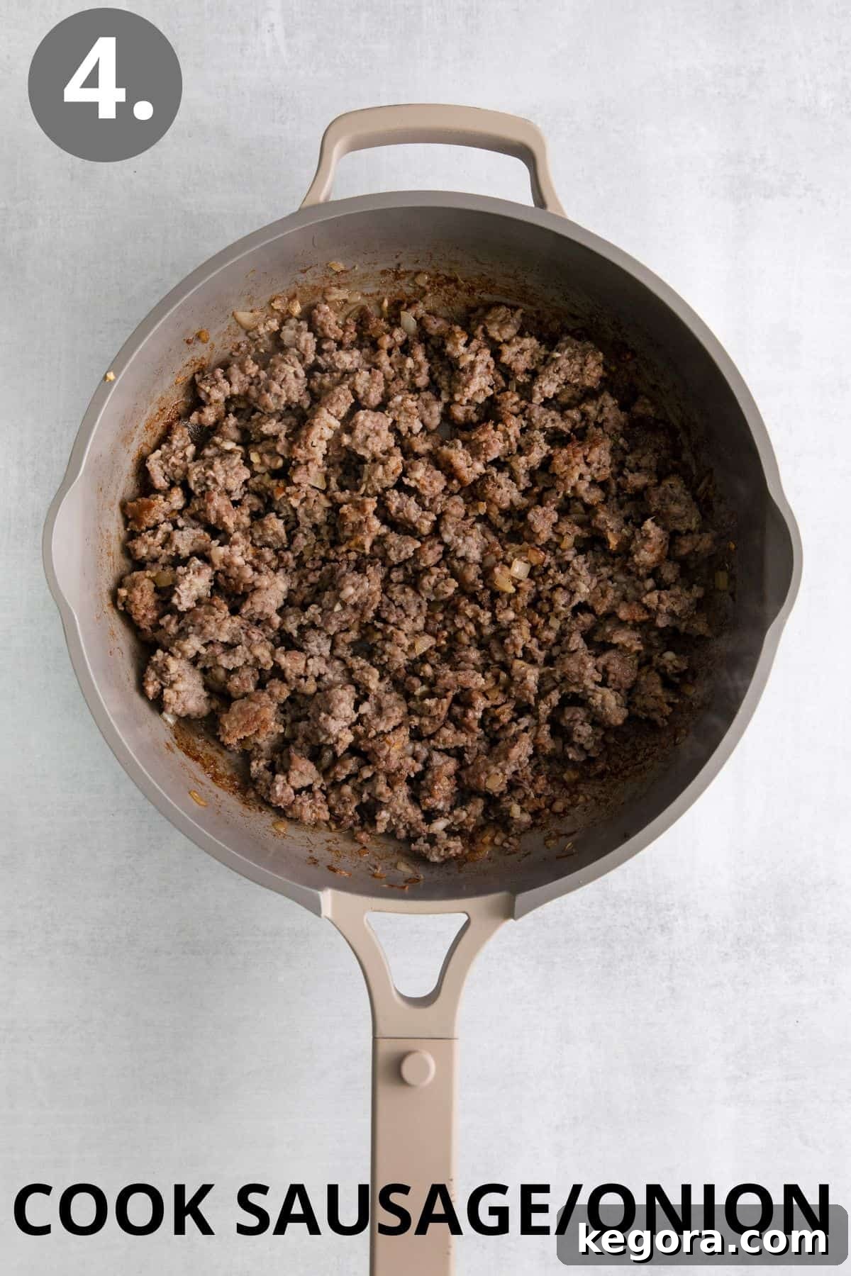 Crumbled ground pork sausage browning in a large skillet on the stovetop.
