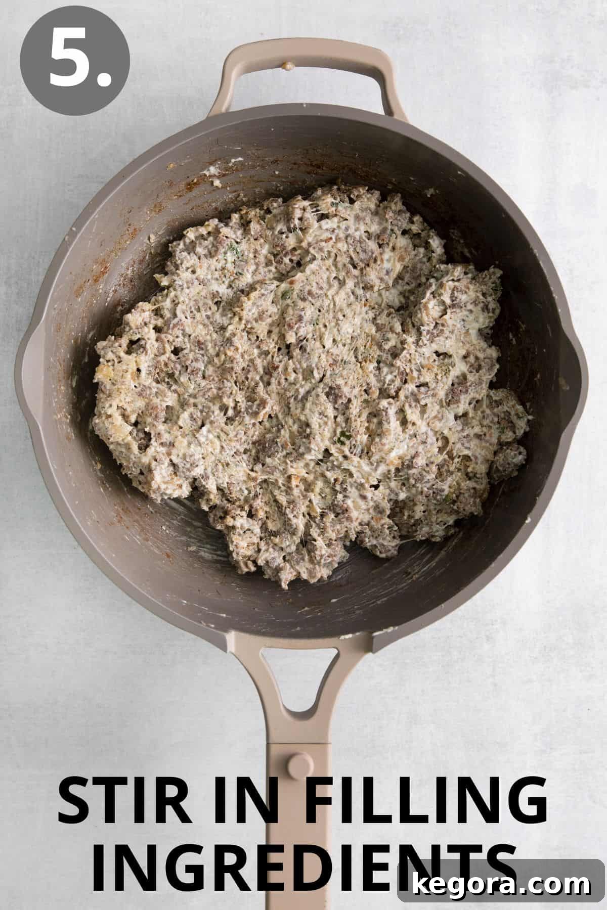 The sausage, onion, and garlic mixture combined with melted cream cheese and Parmesan in a skillet.