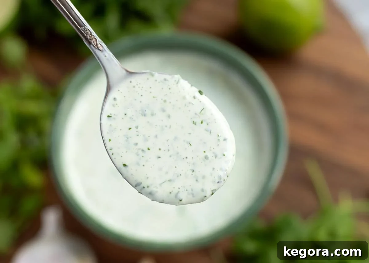 Vibrant Cilantro Cream 4 A spoonful of rich, green Cilantro Cream Sauce being lifted from a vibrant green bowl, showcasing its creamy texture