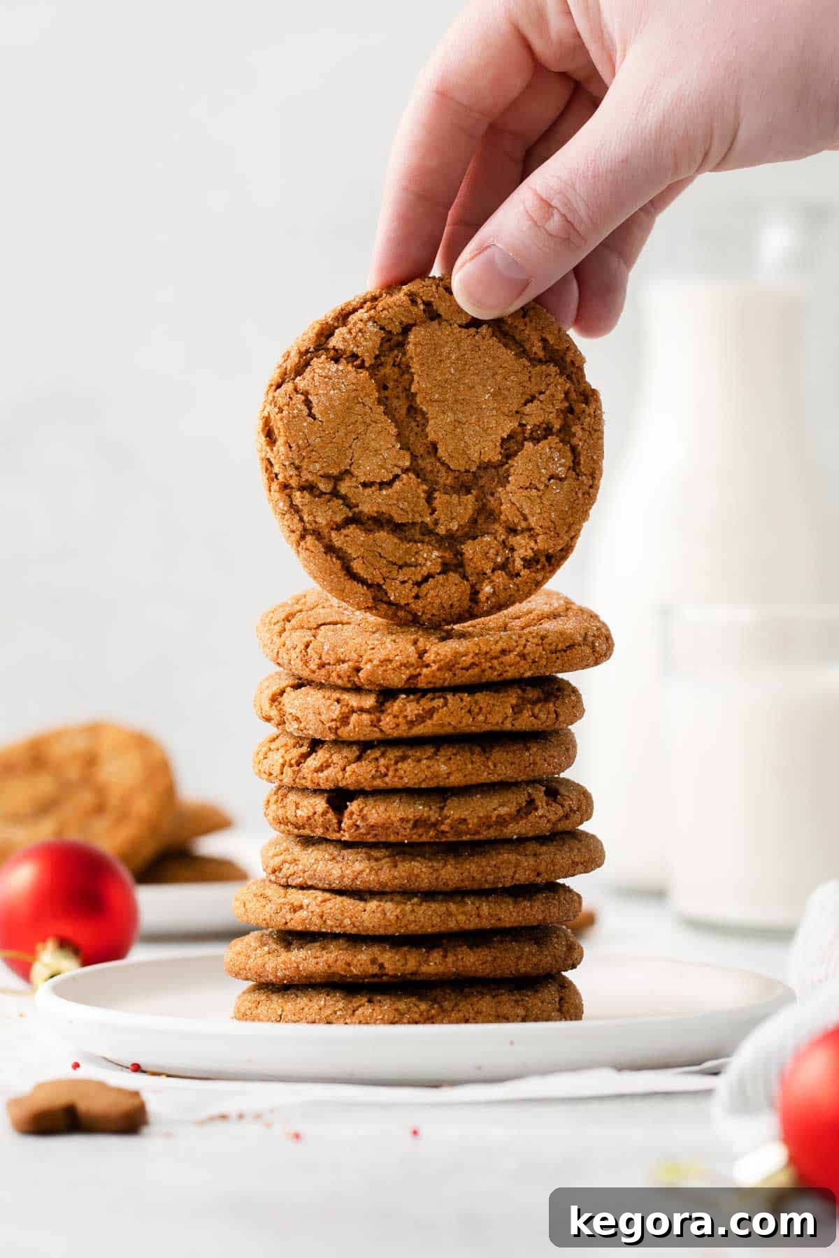 Zesty Gluten-Free Ginger Bites 3 A stack of gingersnaps with a hand picking up the cookie on top, showcasing the perfect crackly texture.