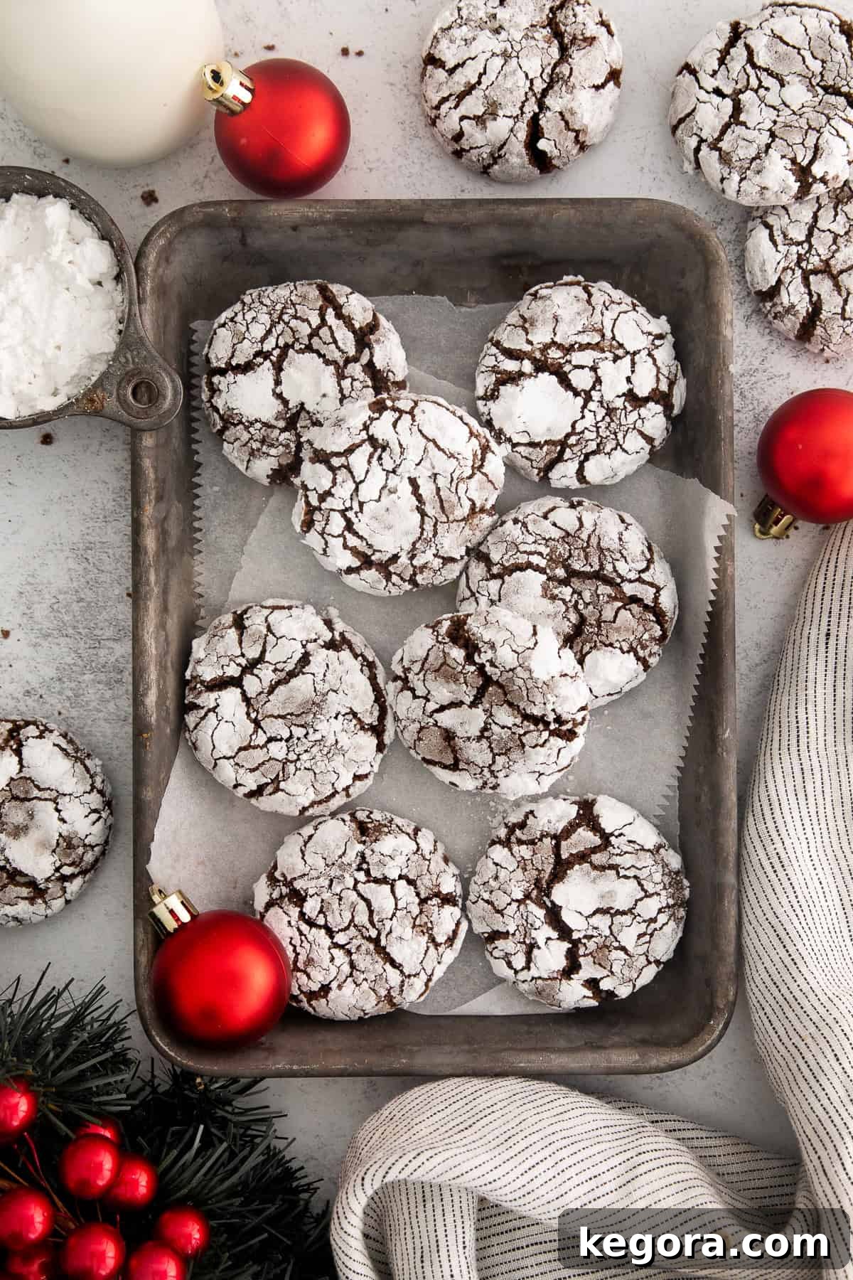 A fresh batch of gluten-free chocolate crinkle cookies cooling on a baking sheet lined with parchment paper.