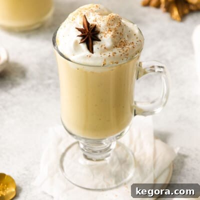 Egg nog served in a glass cup with a handle, topped with whipped cream