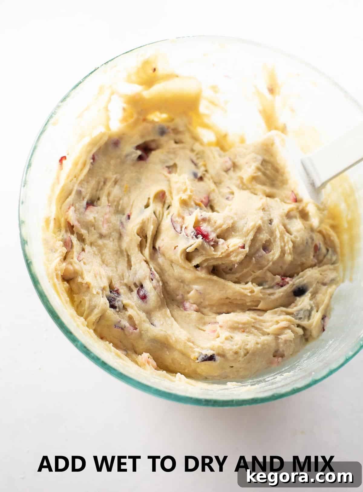 Muffin batter, thick and luscious, in a glass bowl with a white rubber spatula, showing the perfect consistency before adding fruit.