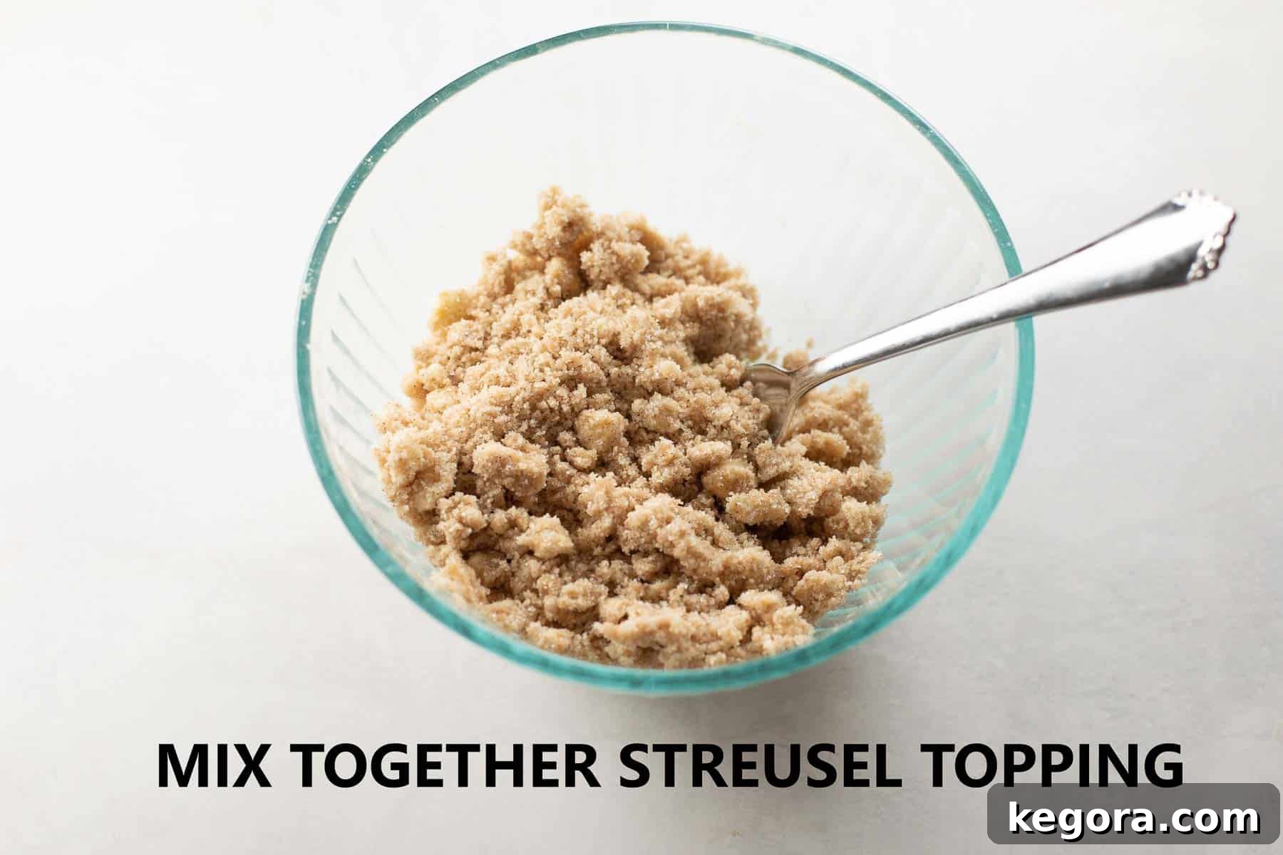 A small glass bowl filled with streusel topping, a delightful mix of sugar, flour, and butter, forming pea-sized clumps.