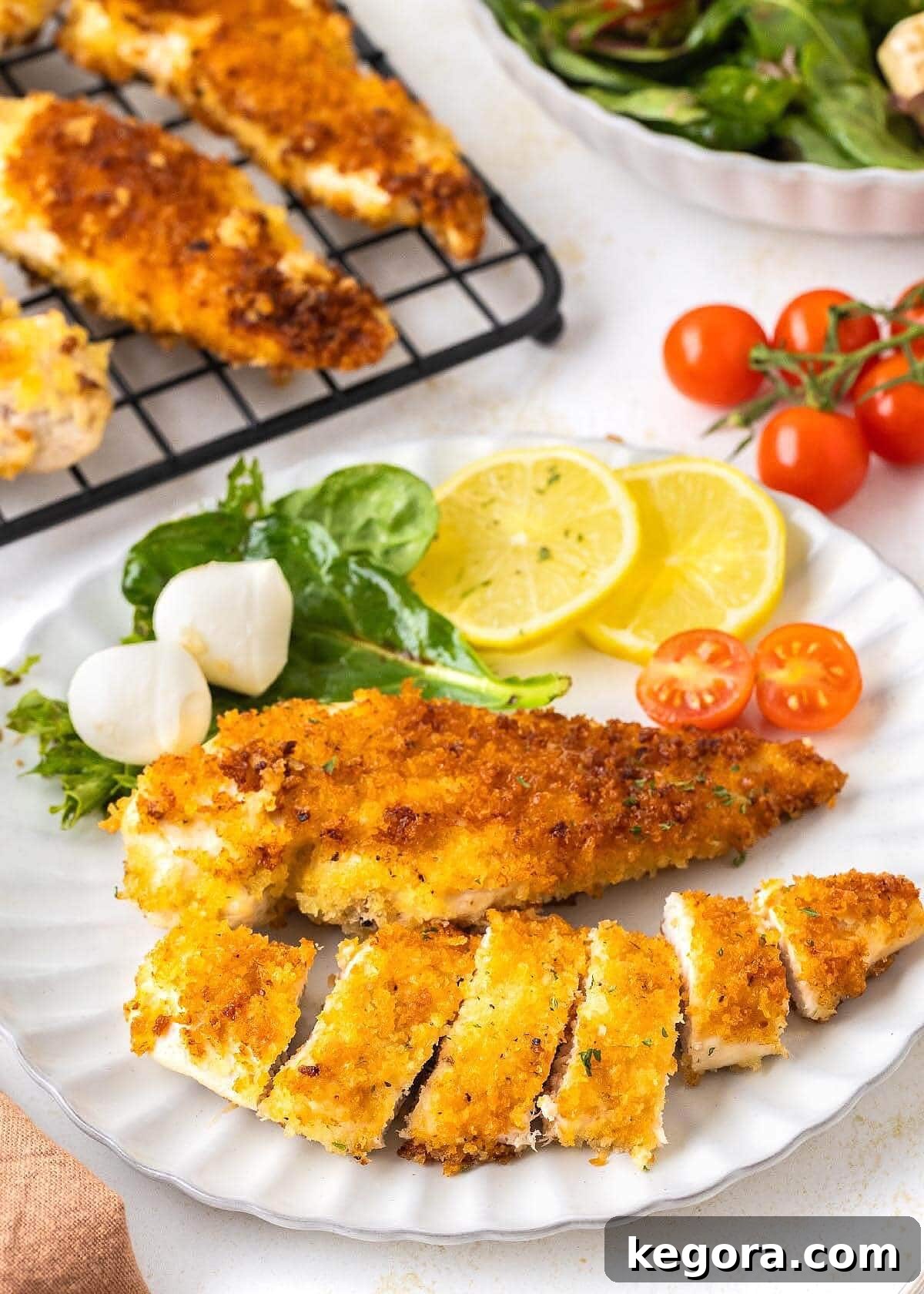 Crispy Skillet Chicken Cutlets 2 Crispy Pan-Fried Chicken Cutlets served on a white plate with a fresh green salad, showcasing their golden brown perfection and inviting texture.