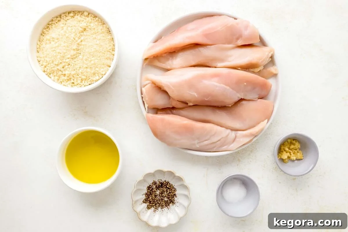 Crispy Skillet Chicken Cutlets 4 A selection of ingredients laid out for pan-fried breaded chicken cutlets, including chicken breasts, panko breadcrumbs, olive oil, and various spices arranged neatly.