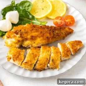 Crispy Pan-Fried Chicken Cutlets on a white plate with salad