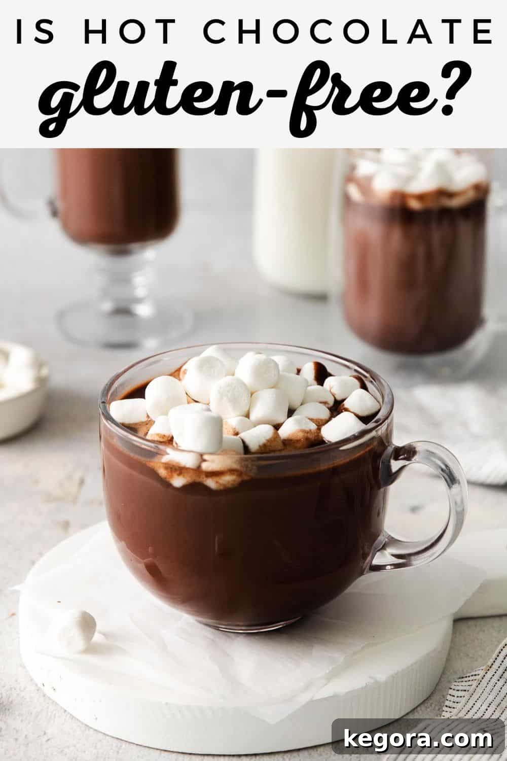 A glass mug of hot chocolate with marshmallows on top, and more mugs of hot chocolate in the background, signaling comfort and warmth