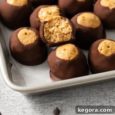 A close-up photo of peanut butter balls with Rice Krispies on a baking sheet