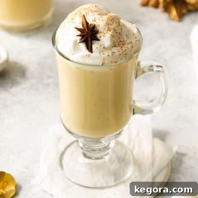 Egg nog served in a glass cup with a handle, topped with whipped cream
