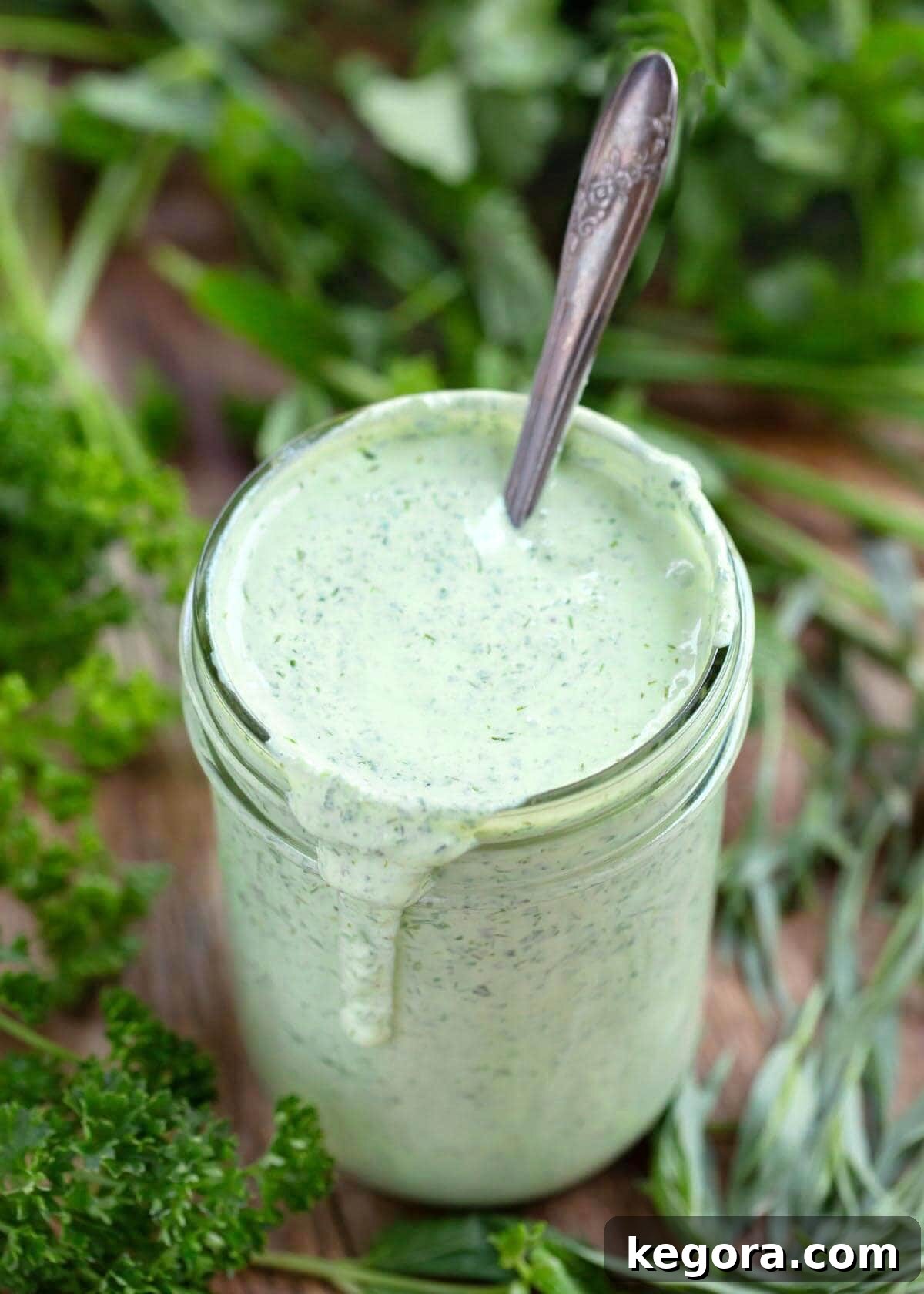 herb yogurt salad dressing in a jar with spoon in it