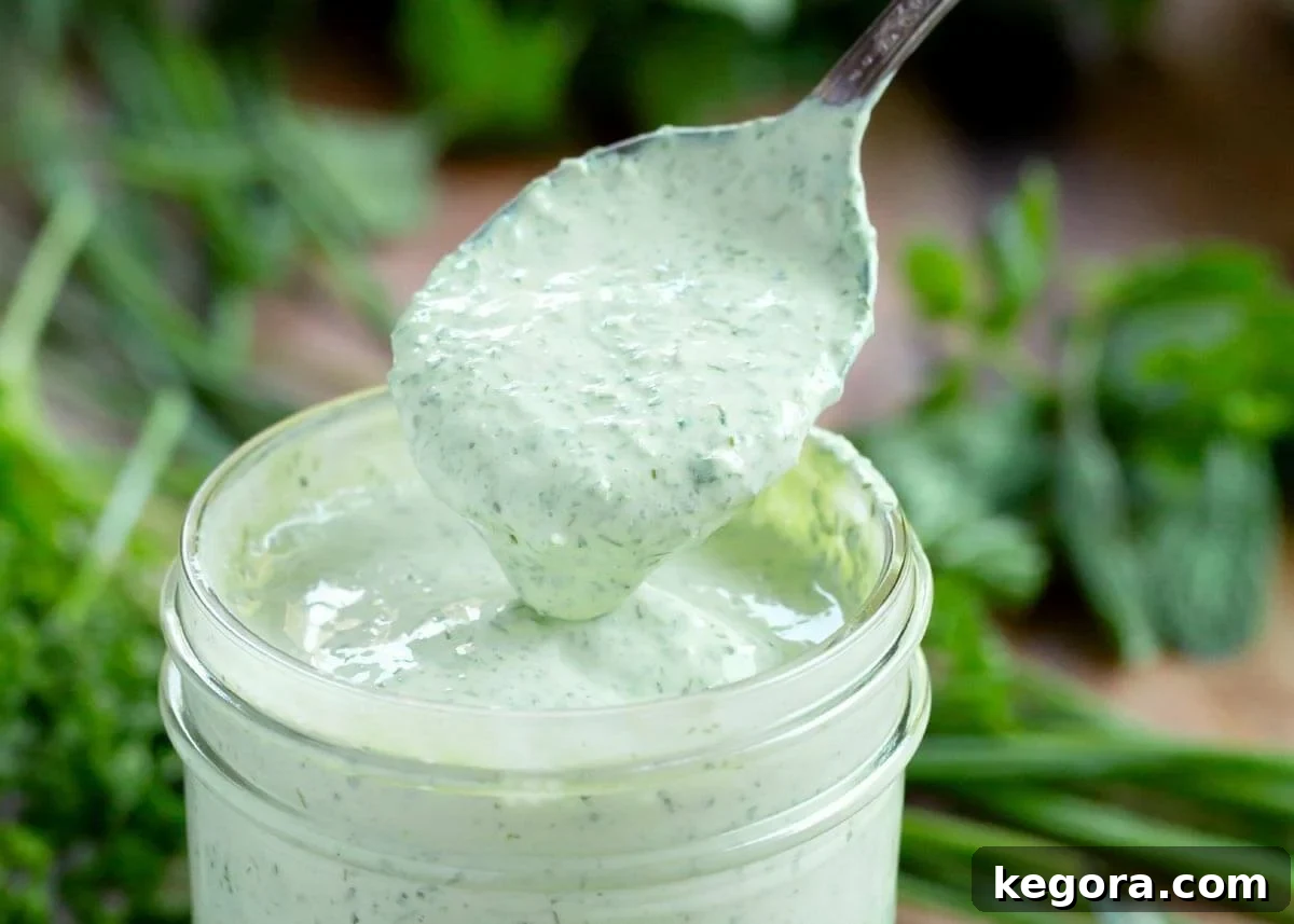herb yogurt salad dressing in a jar with spoonful above it.