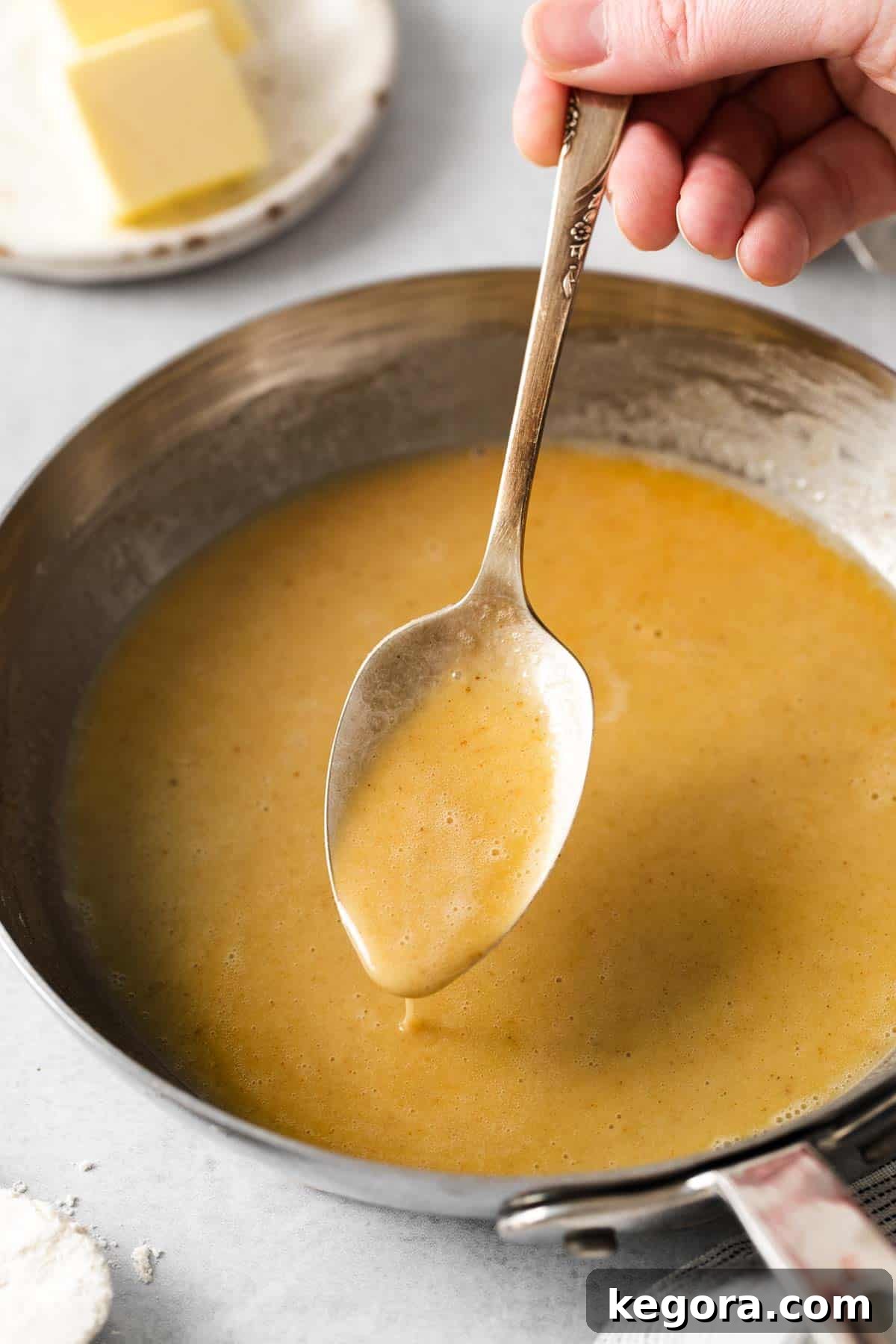 Easy Gluten-Free Roux 7 A close-up of light golden gluten-free roux in a stainless steel skillet with a wooden spoon.