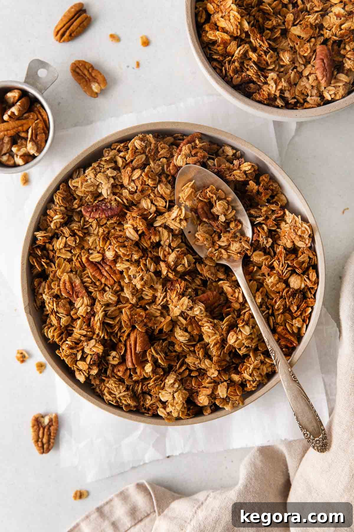 An overhead view of golden brown, crunchy Gluten-free granola in a rustic bowl with a wooden spoon, ready to be enjoyed.