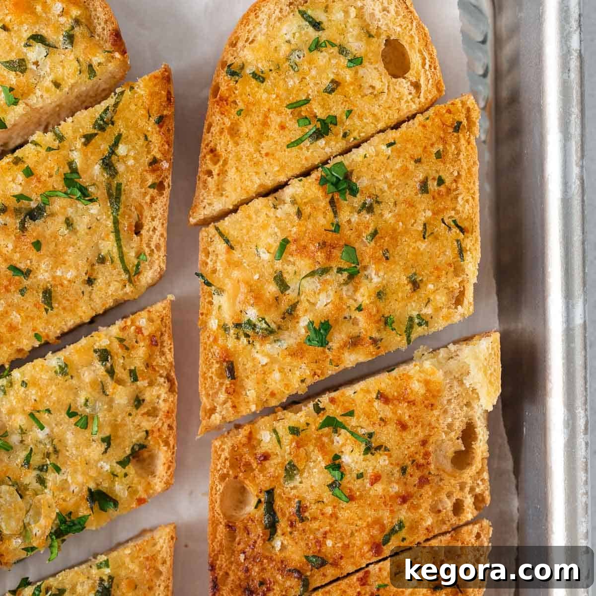 A close-up photo of perfectly toasted gluten-free garlic bread, showing its golden-brown crust and herb flecks.