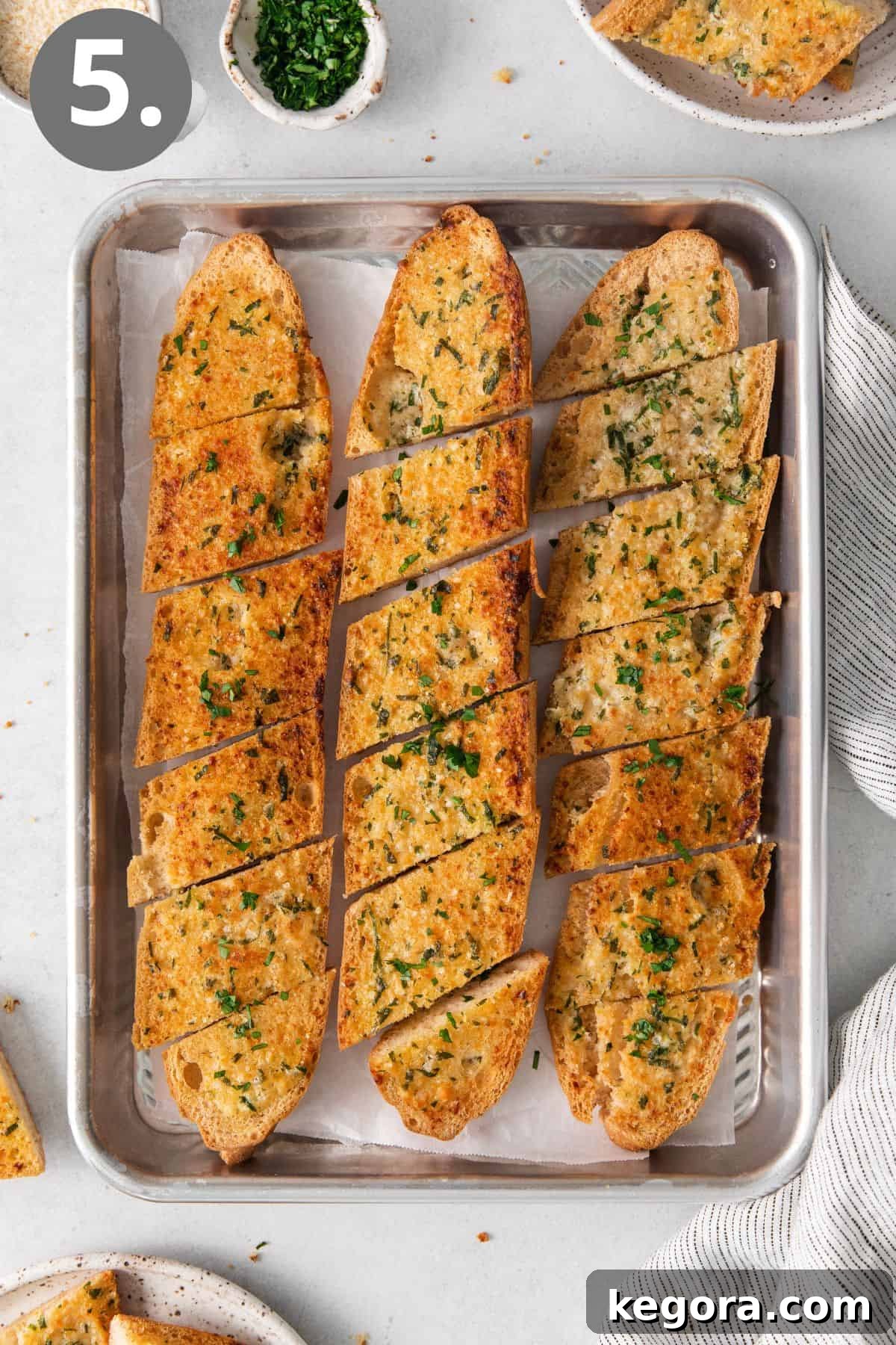 Freshly baked gluten-free garlic bread on a baking sheet, golden brown and ready to slice.