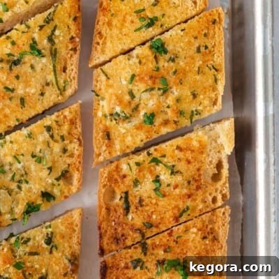 An overhead view of gluten-free garlic bread sliced on a baking sheet, ready to serve.