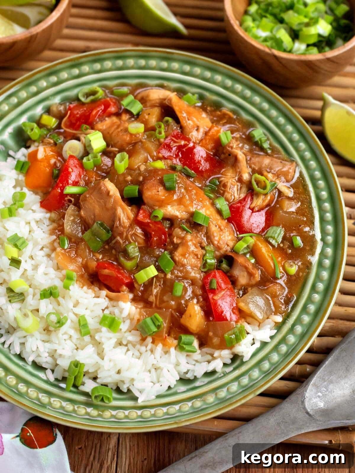 Slow Cooker Pineapple Chicken on a green plate with rice, garnished with fresh herbs.