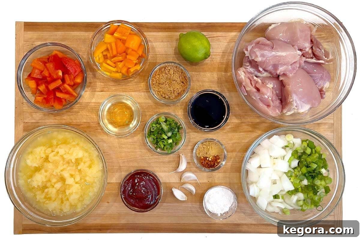 A flat lay shot of all the ingredients for Slow Cooker Pineapple Chicken laid out on a wooden board.