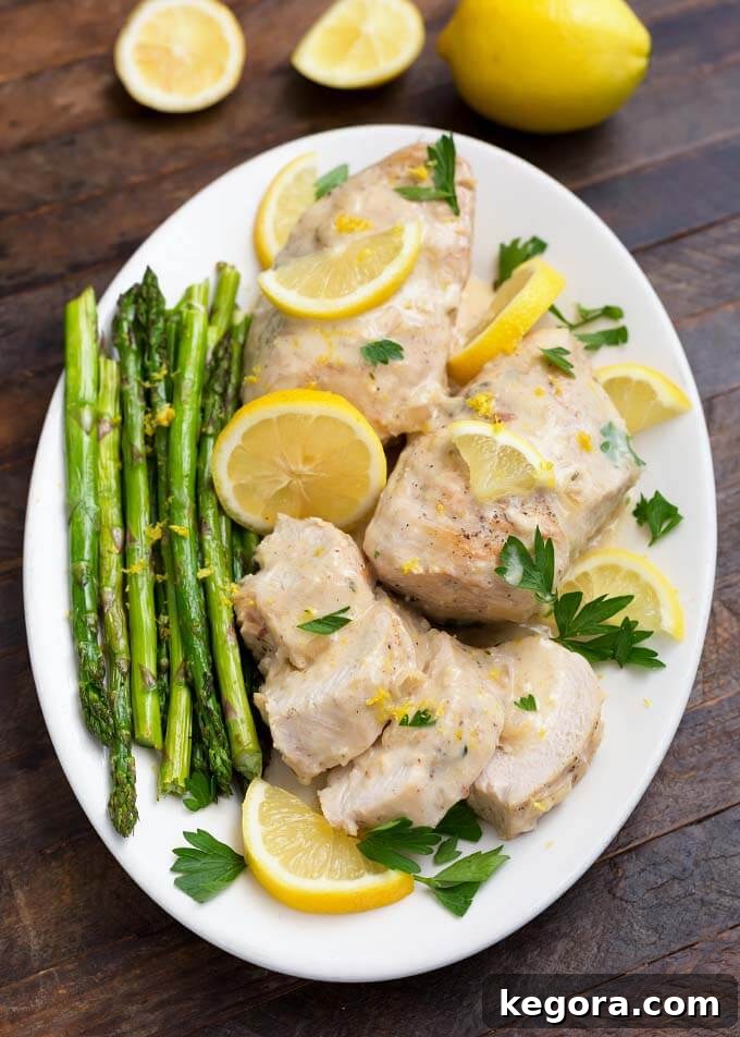 Creamy Lemon Chicken with asparagus on a white oblong plate on wooden table