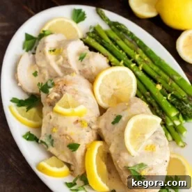 Creamy Lemon Chicken with asparagus on a white oblong plate on wooden table