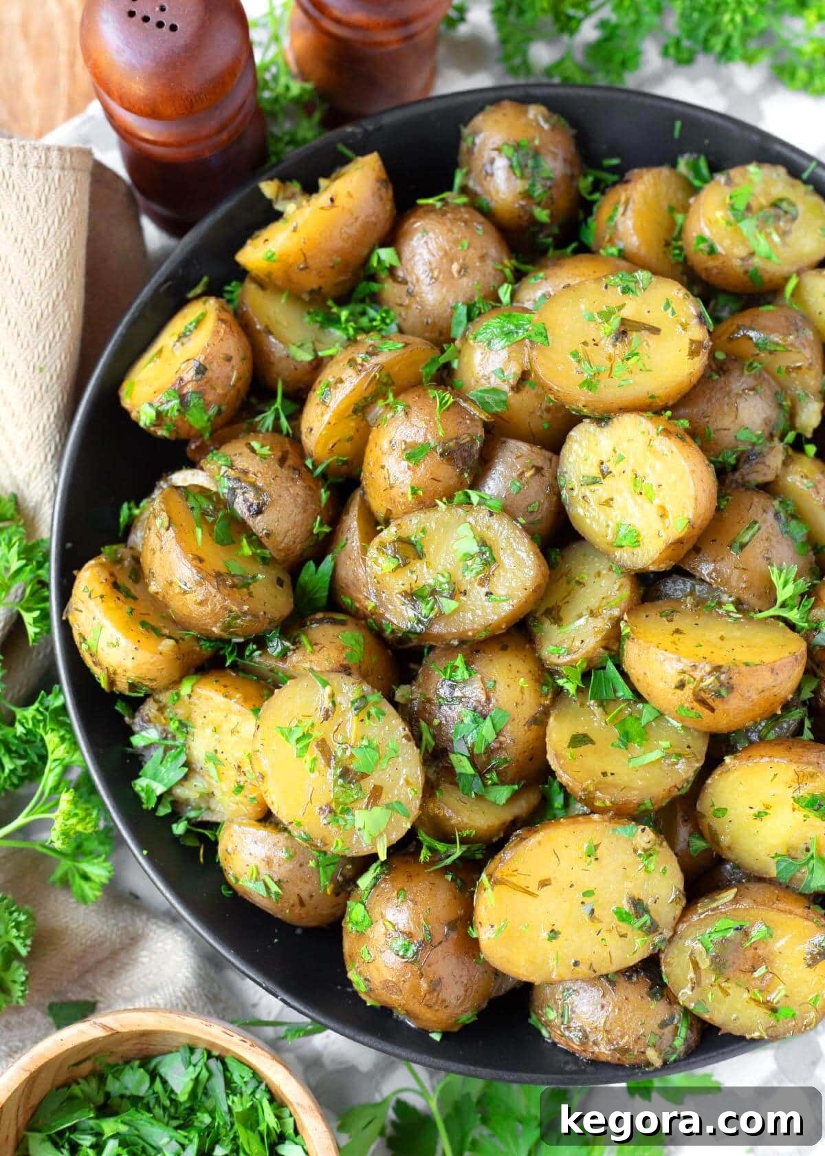 Savory Garlic Herb Slow Cooker Potatoes 2 Delicious Slow Cooker Garlic Herb Potatoes served in a black bowl, garnished with fresh herbs