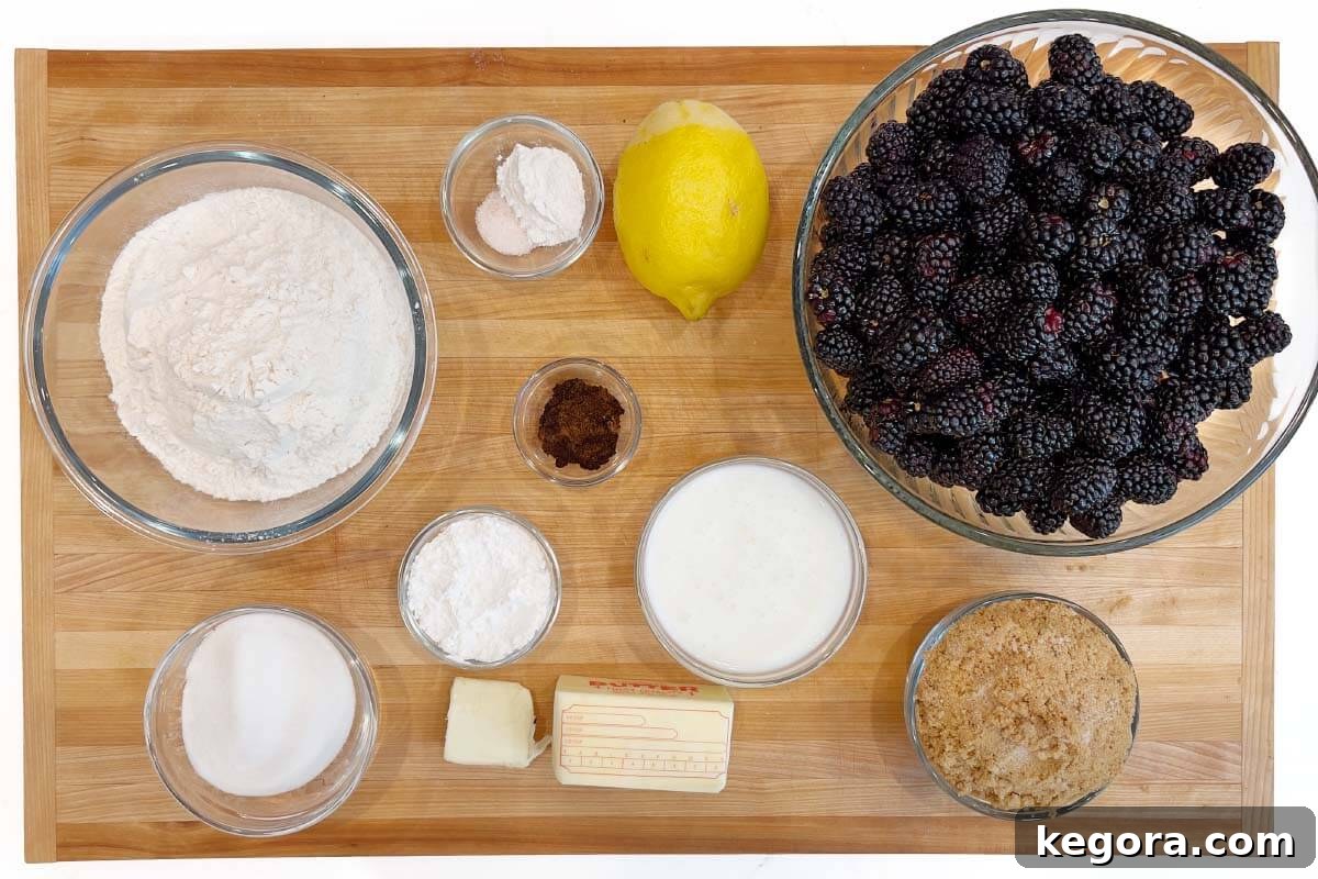 A collection of ingredients for Homemade Blackberry Cobbler laid out on a wooden board, including fresh blackberries, flour, sugar, butter, and lemon.