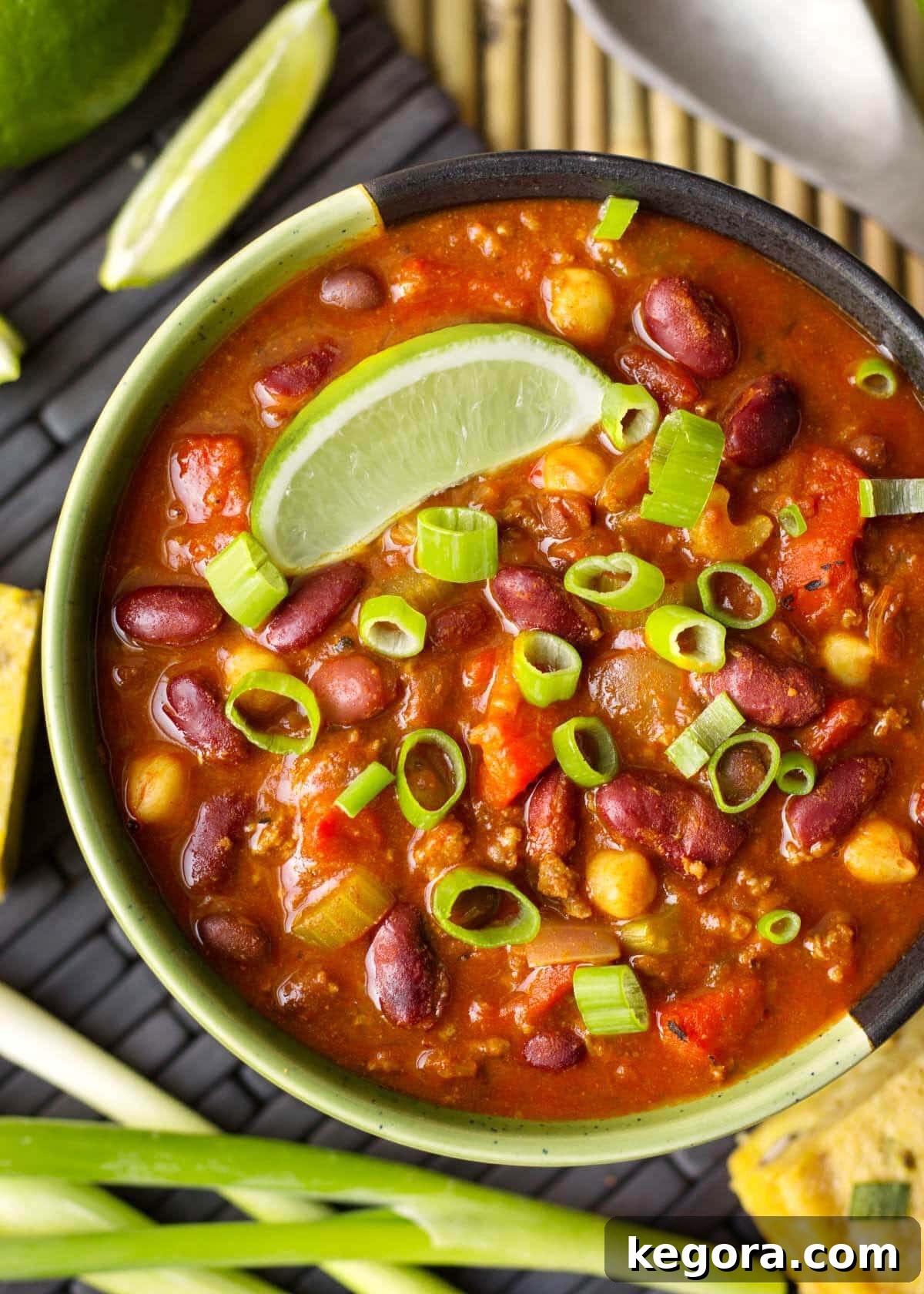 A close-up of a rich bowl of Instant Pot Chili, generously garnished with fresh lime, chopped green onions, and a sprinkle of cheese.