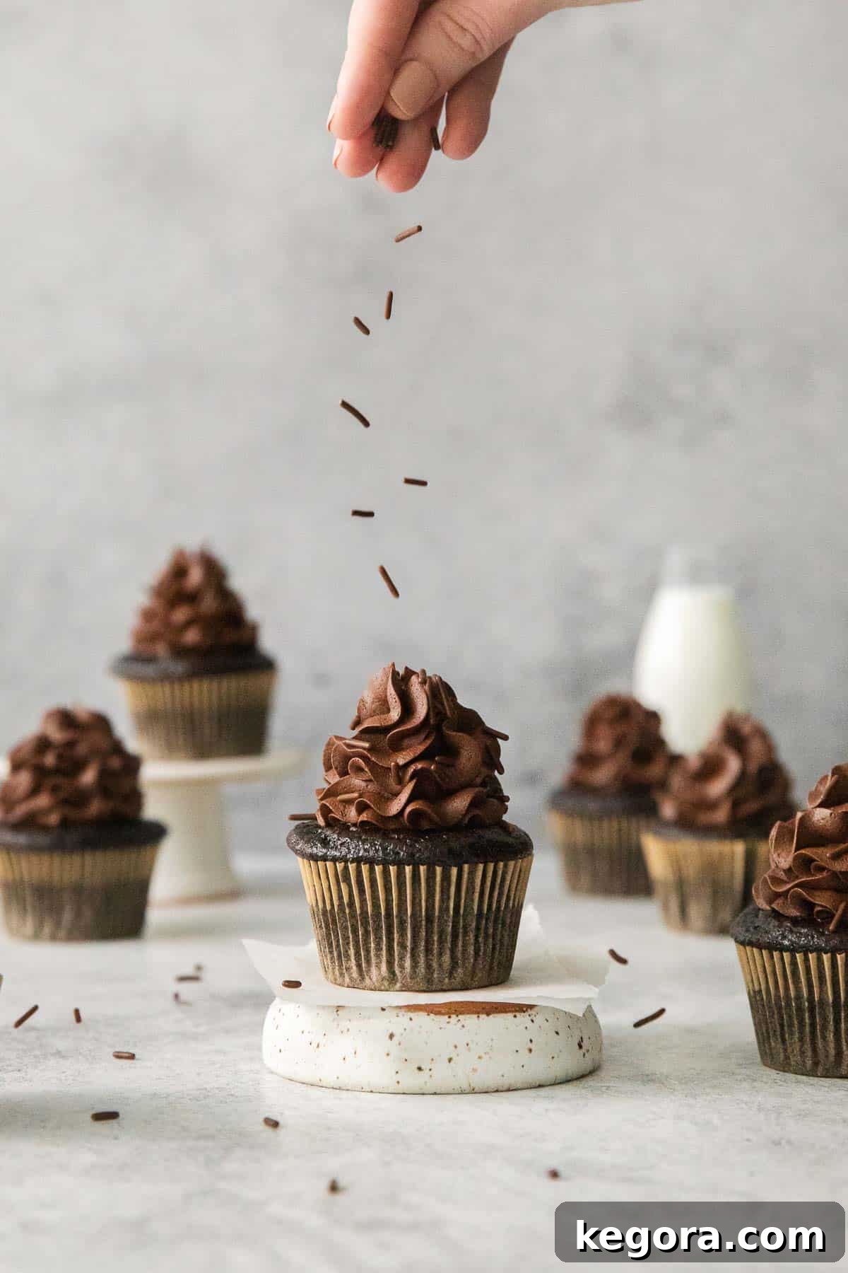 Decadent Gluten Free Chocolate Delights 11 A finished gluten-free chocolate cupcake being delicately dusted with cocoa powder by hand, adding a final touch of elegance.