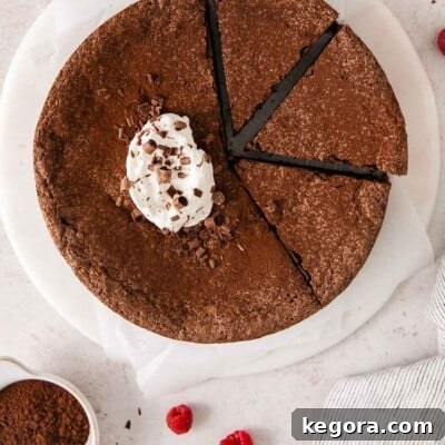 Flourless chocolate torte with whipped cream and cocoa on top on a plate