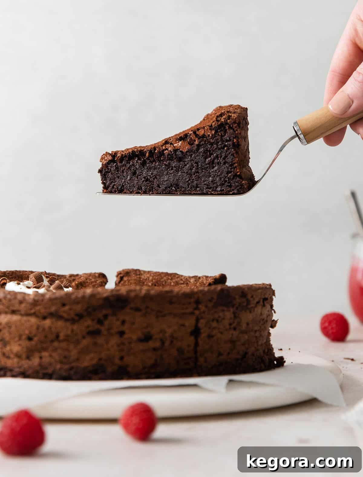 A side view of a slice of flourless chocolate torte being lifted, showcasing its dense, fudgy interior and crackled top.