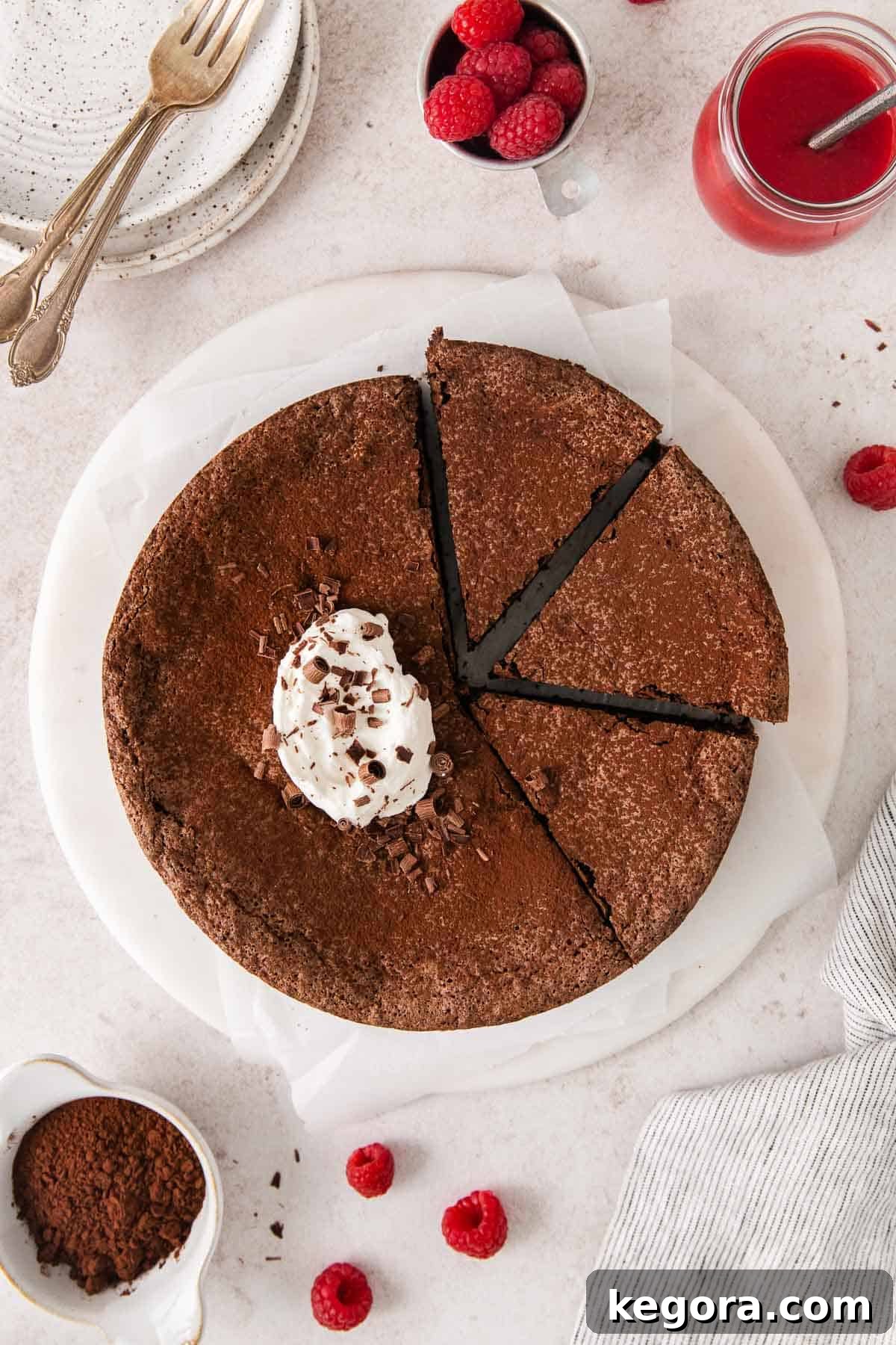 An inviting overhead view of a whole flourless chocolate torte on a serving plate, dusted lightly with cocoa powder.