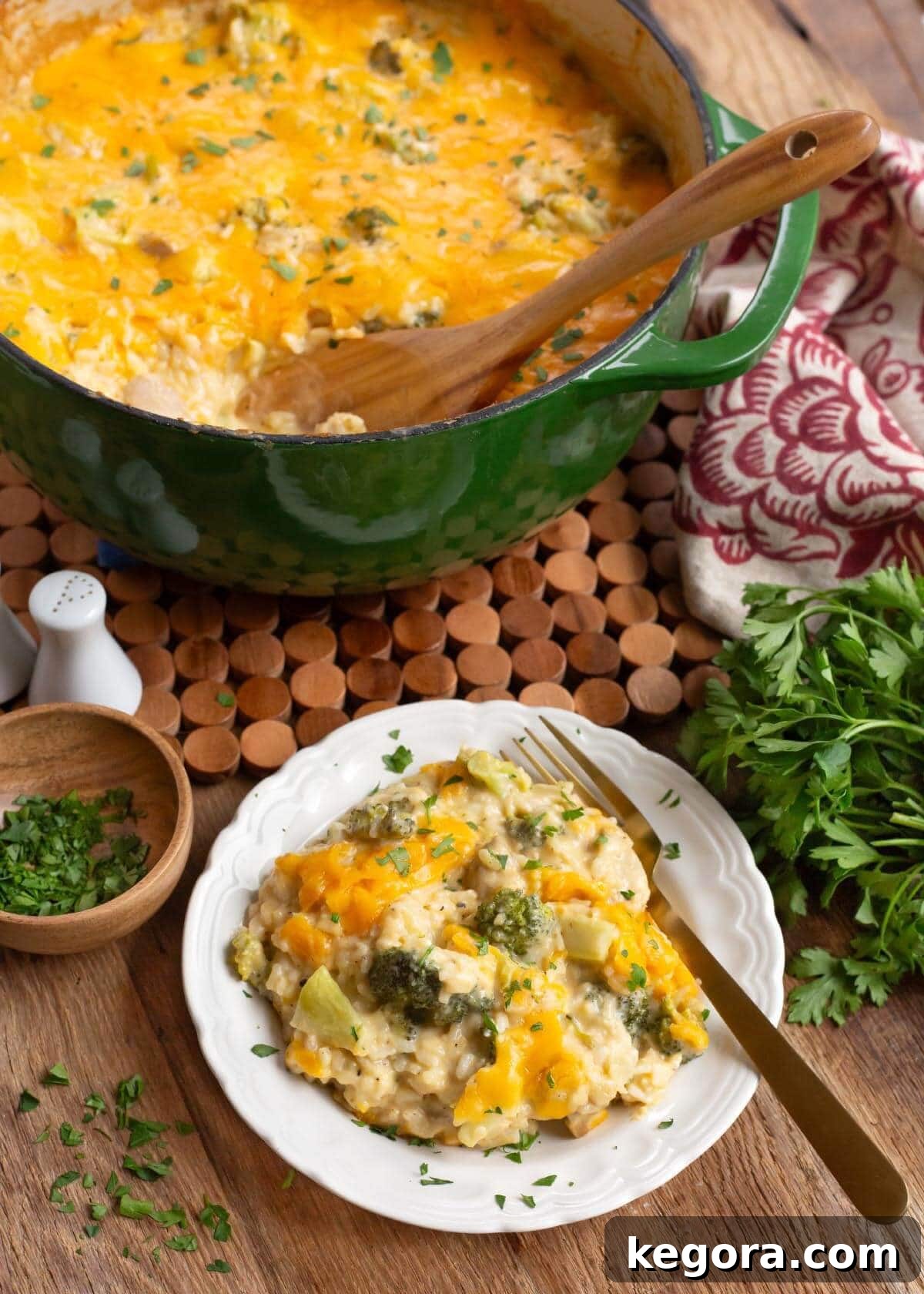 Creamy Cheddar Chicken Broccoli Rice Bake 2 A serving of Cheesy Chicken Broccoli Rice Casserole on a white plate with a green cooking pot in the background.