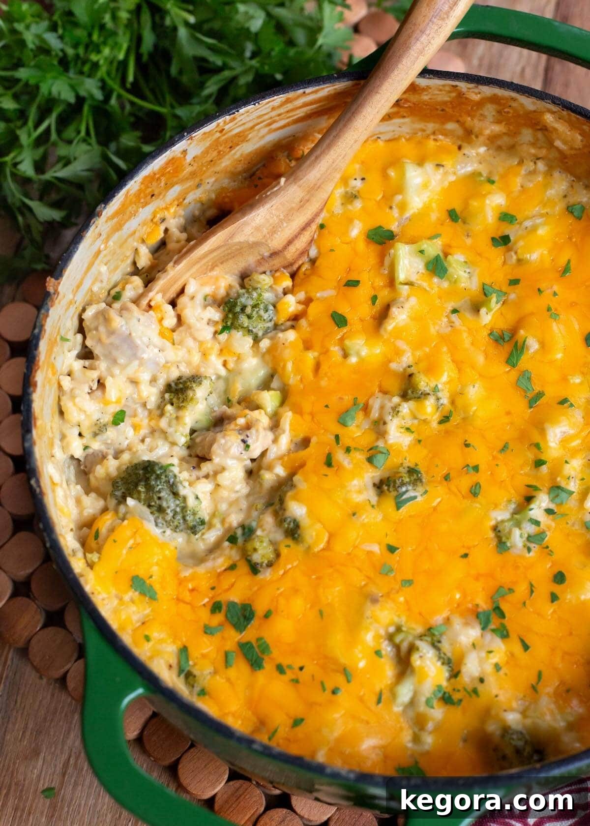 Creamy Cheddar Chicken Broccoli Rice Bake 13 A large pot filled with Cheesy Chicken Broccoli Rice Casserole, with a wooden spoon resting inside.