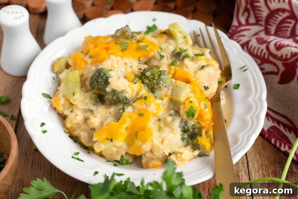 Creamy Cheddar Chicken Broccoli Rice Bake 3 A portion of Cheesy Chicken Broccoli Rice Casserole on a white plate with a fork ready to scoop.