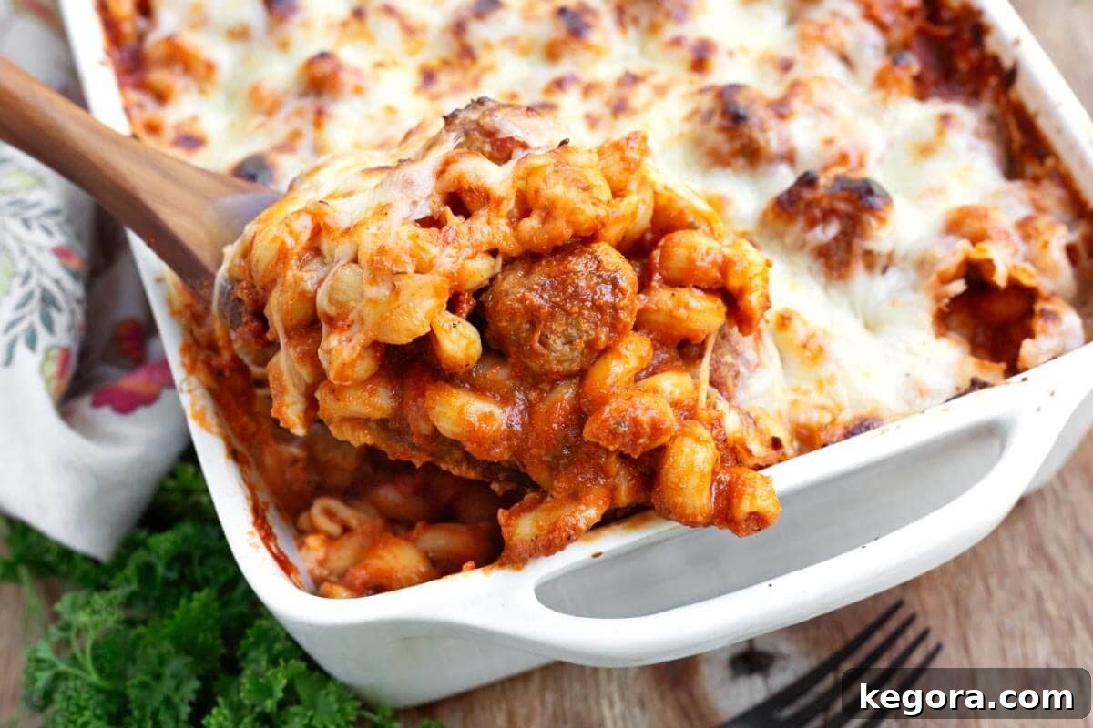 Easy Meatball Pasta Bake in white baking dish on spoon