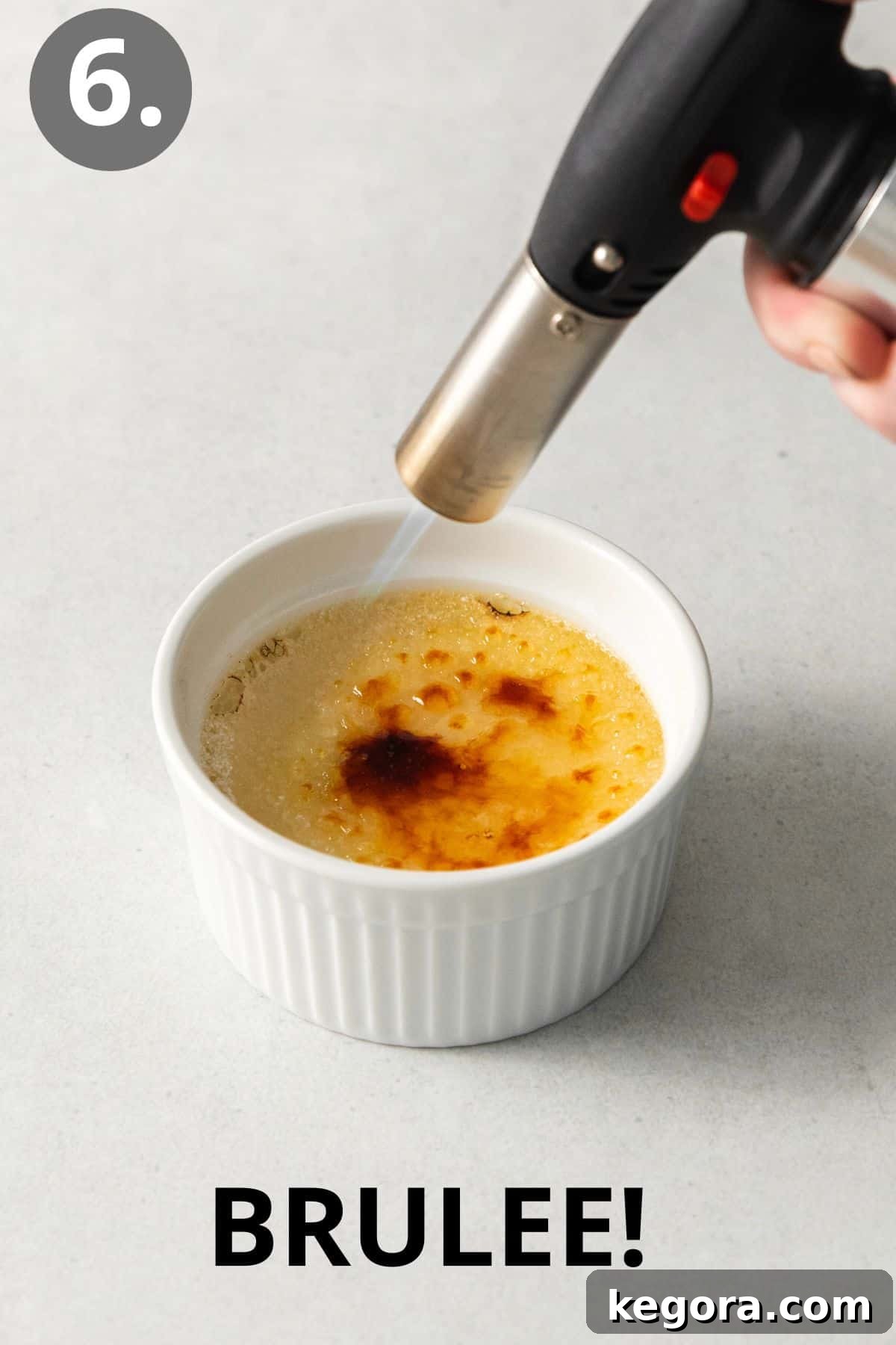 Dairy-Free Dream Brûlée 9 A hand skillfully using a kitchen torch to caramelize the granulated sugar on top of a dairy-free creme brulee ramekin, creating a perfect golden-brown crust.