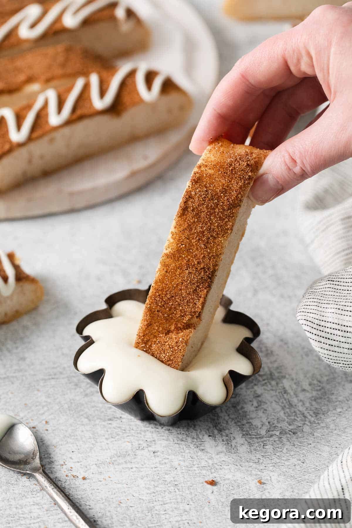 Sweet Cinnamon Gluten-Free Dippers 9 A hand dipping a cinnamon breadstick in glaze