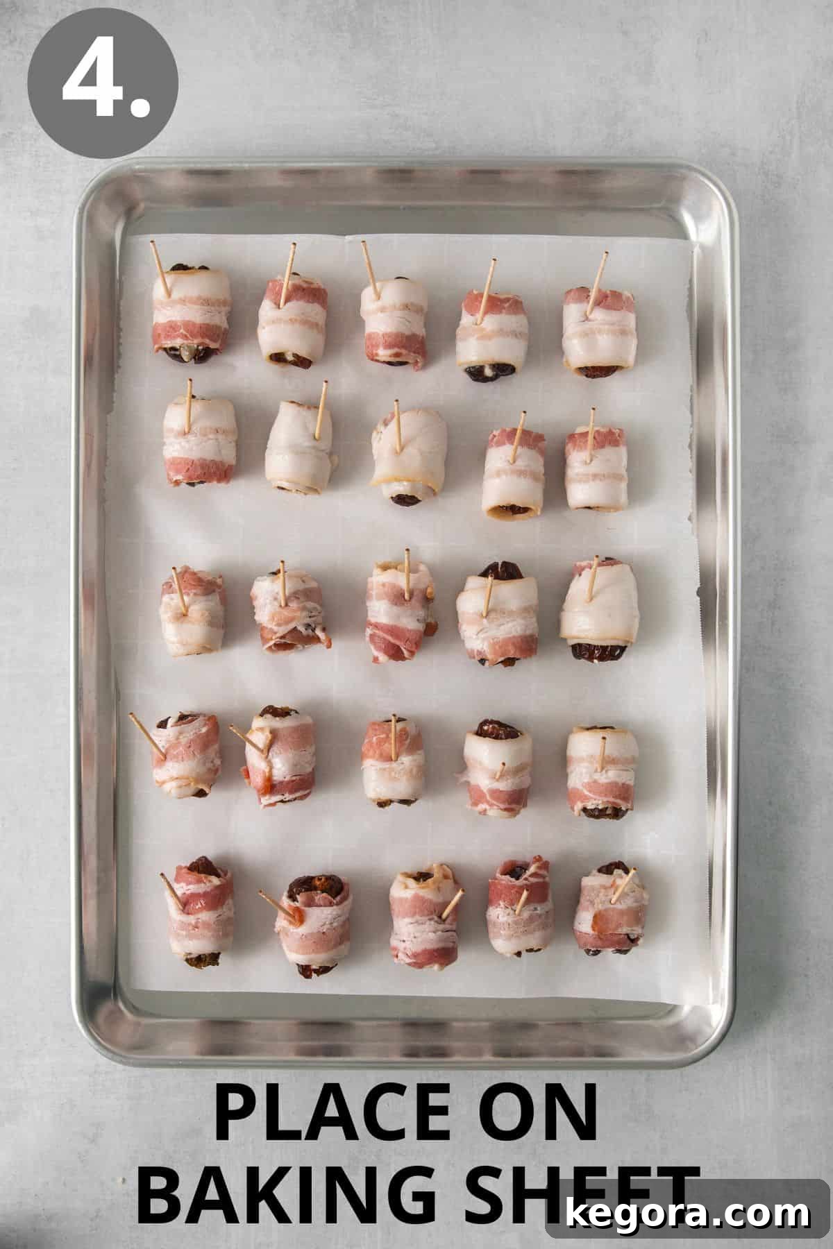 Raw bacon-wrapped dates neatly arranged on a rimmed baking sheet.